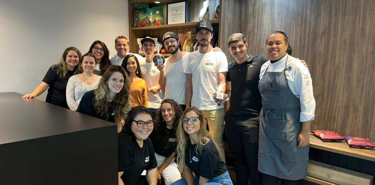 equipe de 14 pessoas uma ao lado da outra que fez parte do projeto com fundo de estante de produtos da barry callebaut