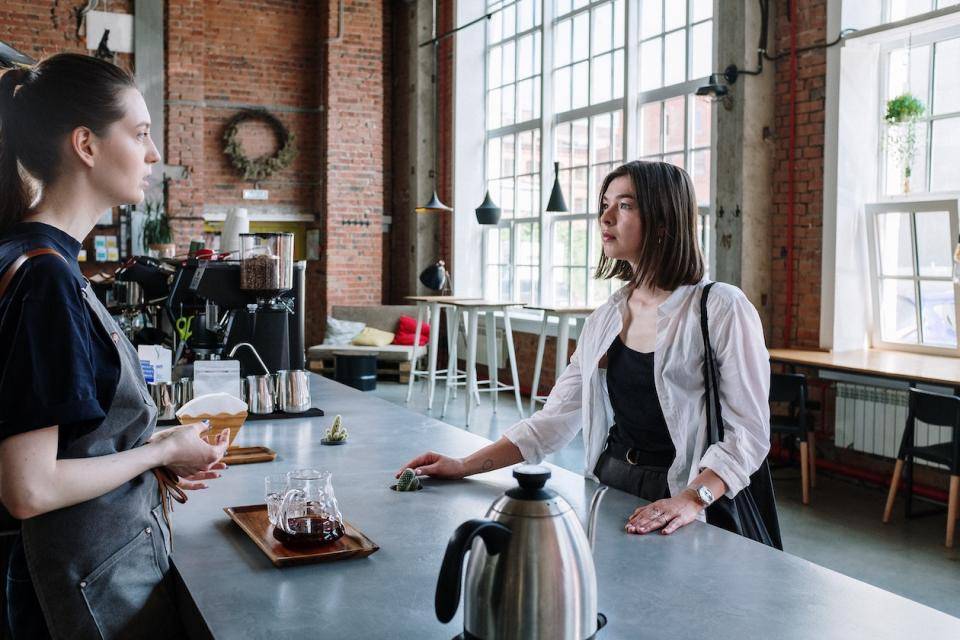 A proprietor and concerned customer chat over the bakery counter