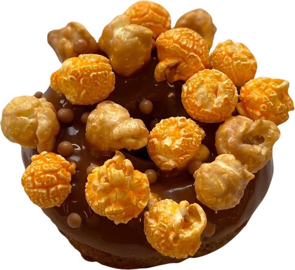 A chocolate doughnut garnished with caramel and cheese popcorn