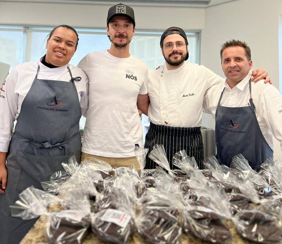 quatro pessoas lado a lado com bancada cheia de cookies a frente