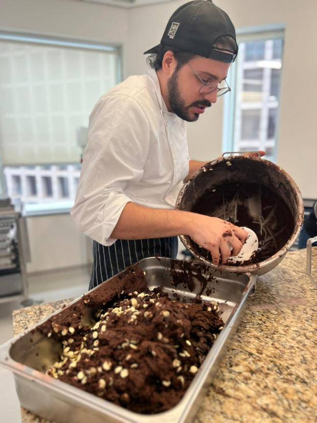 Chef martin segurando um bowl e passando a espatula na massa de cookie para transferir para forma